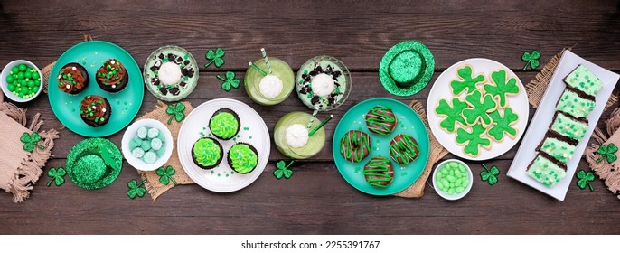 St Patricks Day theme desserts. Table scene over a dark wood banner background. Shamrock cookies, green cupcakes, brownies, donuts and sweets. Top down view. - Powered by Shutterstock
