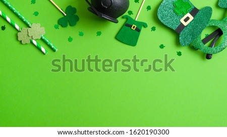 St Patrick's day top frame border of shamrock four leaf clover, pot of gold, Patricks Day glasses, felt hat, drinking straws on green background. Patricks day party invitation template, greeting card