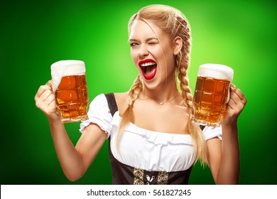 St Patricks Day. Young sexy Oktoberfest waitress, wearing a traditional Bavarian dress, serving big beer mugs on blue background with copy space