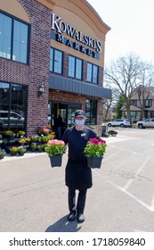 ST PAUL, MINNESOTA / USA - APRIL 26, 2020: Kowalski's Market Charming Door Greeter Delivers Two Pots Of Flowers To The Car Observing A Safe Social Distance. 