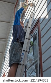 ST PAUL, MINNESOTA USA - AUGUST 18, 2021: Teen On A Ladder Painting A House.