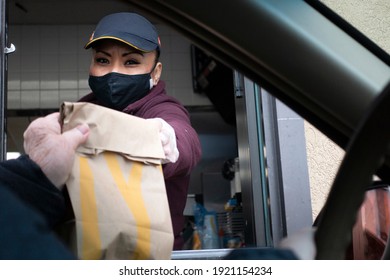 ST PAUL, MINNESOTA USA - JANUARY 23, 2021: McDonald's Food Service Worker Masked Handing Food To Customer In Car.