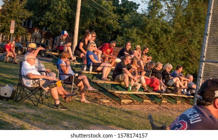 ST PAUL, MINNESOTA / USA - JULY 09, 2017: Fans At Sunset In Bleachers At School Baseball Game While Several Work Their Cell Phones. 