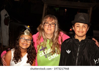 ST PAUL, MINNESOTA USA - OCTOBER 31, 2018: Latino Halloween trick or treaters costumed as a princess and escort in black with their mom.