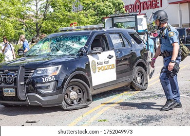 St. Paul, MN/USA - 06/4/2020 police officer is investigating a heavily damaged cop car in the middle of race riots in St. Paul, MN. The officers armed, with full gear. Rioters destroyed the vehicle