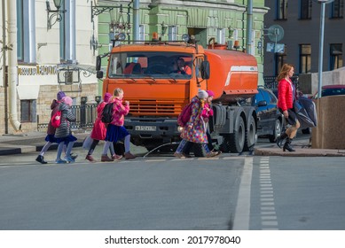 ST. PETEBURG, RUSSIA - APRIL 18, 2021: Schoolchildren Cross The Street In Front Of A City Utility Truck