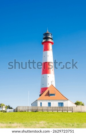 St Peter Ording Lighthouse in Westerhever surrounded by green fields with grazing sheep iconic coastal scene in northern Germany blending nature and maritime heritage