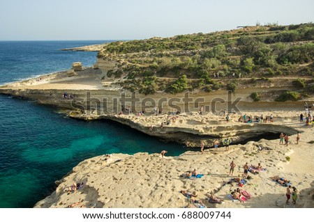 St. Peter's Pool in summer, Marsaxlokk, Malta - natural pool wide angle view, tourists enjoying the environment