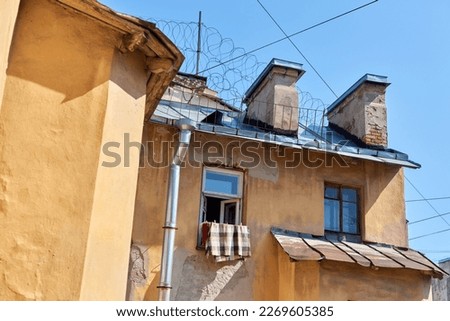 St. Petersburg facade of yellow communal house with windows and roof in sunny day against the background of blue sky. Warm earthy shades Authentic view of old city Dark walls muck up. Retro style