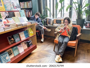 St. Petersburg, Russia, August 2021: The Interior Of Modern Cozy Bookstore In A Retro Style. Two Young Hipster Girls Are Sitting, Reading