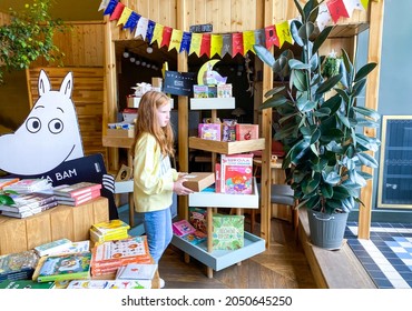 St. Petersburg, Russia, August 2021: A Red-haired Girl With Box In The Childrens Department Of A Modern Cozy Bookstore