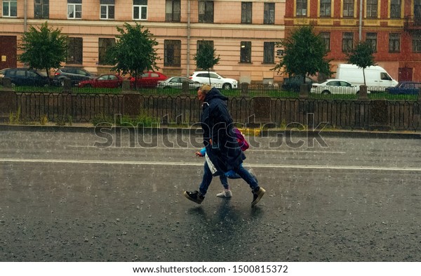 St. Petersburg, Russia - August 8 2019: Get\
caught in the rain. Mother and daughter hurry home in the pouring\
rain, without umbrella