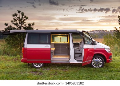 St. Petersburg, Russia - July 22, 2019: Red and white colored modern Volkswagen Multivan California Ocean (Transporter). Is Parked in the forest at sunrise Side view and open doors