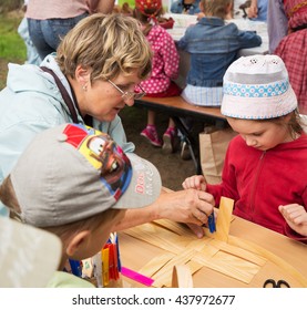 ST. PETERSBURG, RUSSIA - JULY 26, 2015: Unidentified Girl Learns To Weave Bast Basket On A City Fair. Master Class Teaching Children Folk Crafts Weaving A Basket