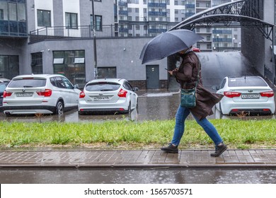 St. Petersburg, Russia June 2019-Murino District, Heavy Rain, Flooding, A Woman With An Umbrella Goes And Looks In The Phone.