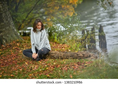 St. Petersburg, Russia, October 30,2017: 
The girl is sitting on a log. The girl enjoys the autumn landscape. Beautiful autumn in the park. The girl thought about life - Shutterstock ID 1383210986