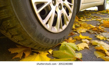 St. Petersburg, Russia - October 4, 2021: Car wheel on road. Yellow dry fallen maple leaves on asphalt. Golden autumn street. Travelling. Driving. Automobile hubcap. Protection auto. Fall. Sailun tire