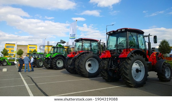St. Petersburg, Russia - September 4, 2020: New\
modern tractors in agricultural machinery exhibition. Venue for\
farmer business and industry. Manufacturing equipment for crop\
production. Blue sky.