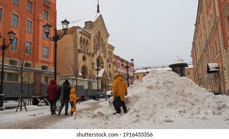 St Petersburg, Russia-02--07--2021: snow-covered Malaya Konyushennaya street, family in bright colored jackets, big snowdrift
