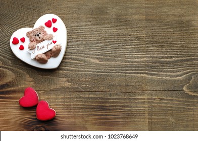 St Valentine's Day Cookies On The Left Side, Two Small Red Hearts, One Big White Heart Cookie Decorated With A Cute Teddy Bear, Wooden Background, Space For Text, Top View