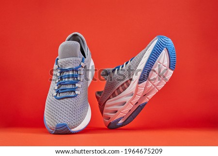 Stability and cushion running shoes. New unbranded running sneaker or trainer on orange background. Men's sport footwear. Pair of sport shoes.