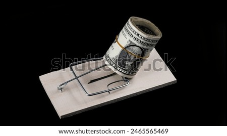 A stack of 1 US dollar bills and a mousetrap on a black background