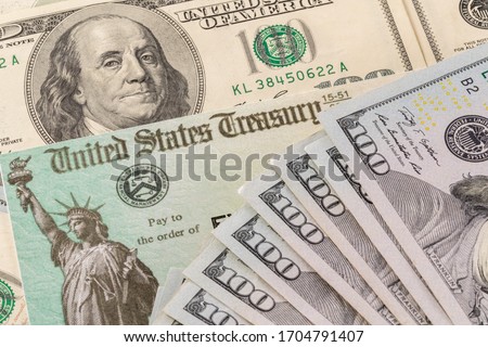 Stack of 100 dollar bills with illustrative coronavirus stimulus payment check to show the virus stimulus payment to Americans