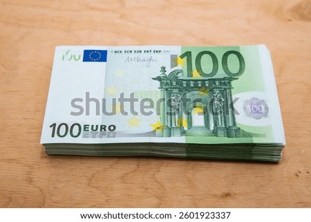 Stack of 100 Euro banknotes on wooden background, top view — concept of savings, finance, investment, and cash wealth in the European Union