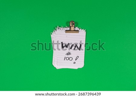 A stack of 100 paper win tickets on a green background as a symbol of winning, gains, growth mindset and the psychology of daily goalsetting.
