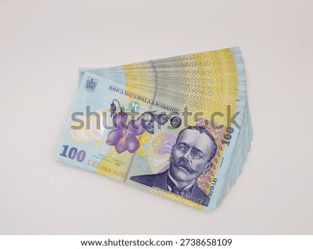 Stack of 100 Romanian Leu (RON) polymer banknotes fanned out on a white background. Features the portrait of writer Ion Luca Caragiale and a blue violet flower.
