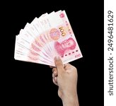 Stack of 100 Yuan currency bills on the black isolated backdrop. Man holding the Chinese currency in hand