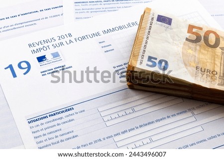 Stack of 50 euro banknotes on the top of a French Property wealth tax form (Impôt sur la fortune immobilière).