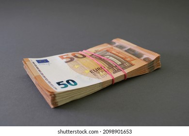 Stack of 50 euro banknotes, tied with rubber band, on a gray-blue background. Euro money. Close up view.