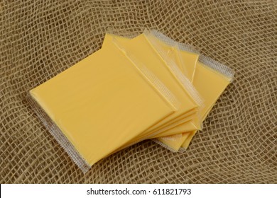 Stack Of American Cheese Slices In Plastic Packaging On Burlap