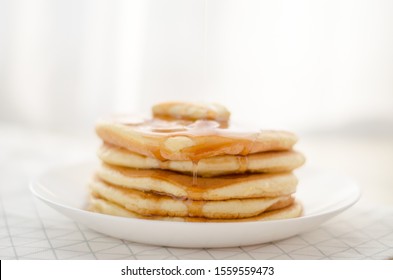 Stack of american pancakes with piece of butter and honey