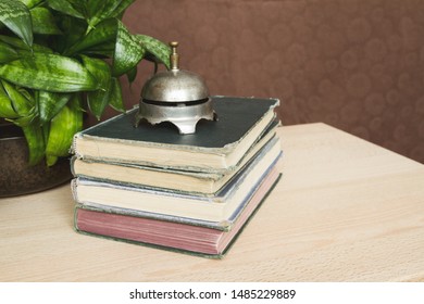 Stack of antique books with a vintage bell on top;  A neat pile of books with a very old bell resting on top.