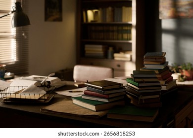 Stack of assorted books arranged on desk in home office with sunlight streaming through window, bookshelf filled with volumes in background, workspace suggesting academic or literary setting
