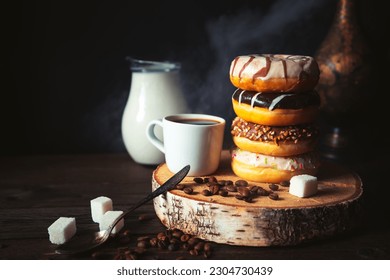 Stack of assorted donuts, a jug of milk and a cup of steaming coffee on a dark background. - Powered by Shutterstock