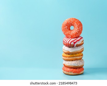 Stack of assorted donuts on blue background. Many colorful glazed doughnut with sprinkles stacked with copy space - Powered by Shutterstock