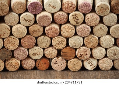 Stack of assorted wine corks on wooden background.