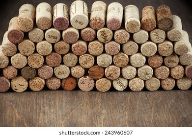 Stack of assorted wine corks on wooden background.