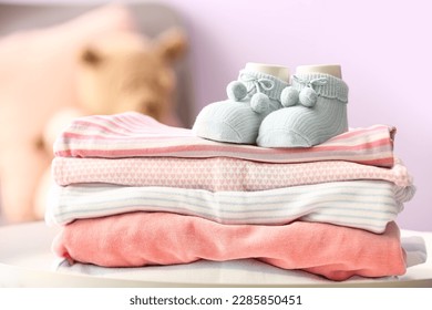 Stack of baby clothes and socks on table in room, closeup