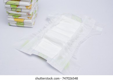 Stack Of Baby Diapers And The Open Diaper In Front