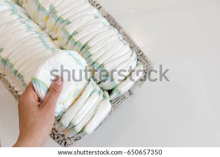Stack of baby disposable diapers and Pacifier over white background