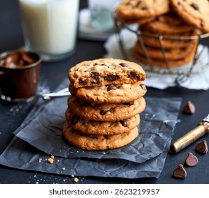 stack of baked round chocolate chip cookies on a black table, close up