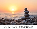 Stack of balanced rocks on beach during sunset, golden hour on the beach
