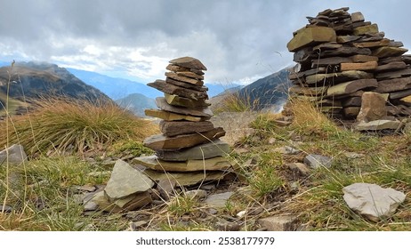 A stack of balanced stones on a mountain trail with misty peaks in the background. The rocky cairn adds a sense of adventure to the rugged alpine landscape. - Powered by Shutterstock