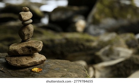 A stack of balanced stones sits on a mossy rock near a Scottish river.