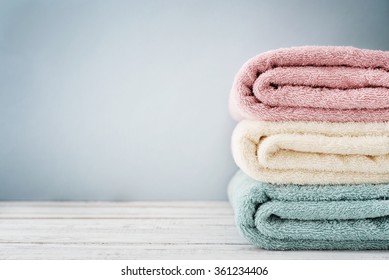 Stack of bath towels on light wooden background closeup