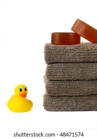 A stack of bath towels and a rubber duck isolated against a white background